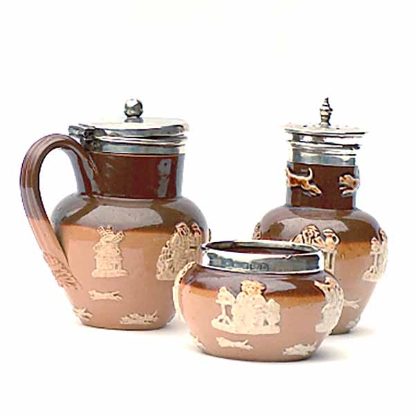 A silver-rimmed Doulton Lambeth 3-piece cruet in hunting/harvest style